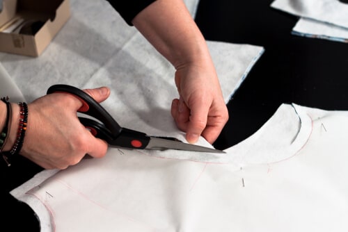 Una persona che cucisce un abito, mostrando le tecniche di cucito e i materiali necessari per creare un abito di qualità